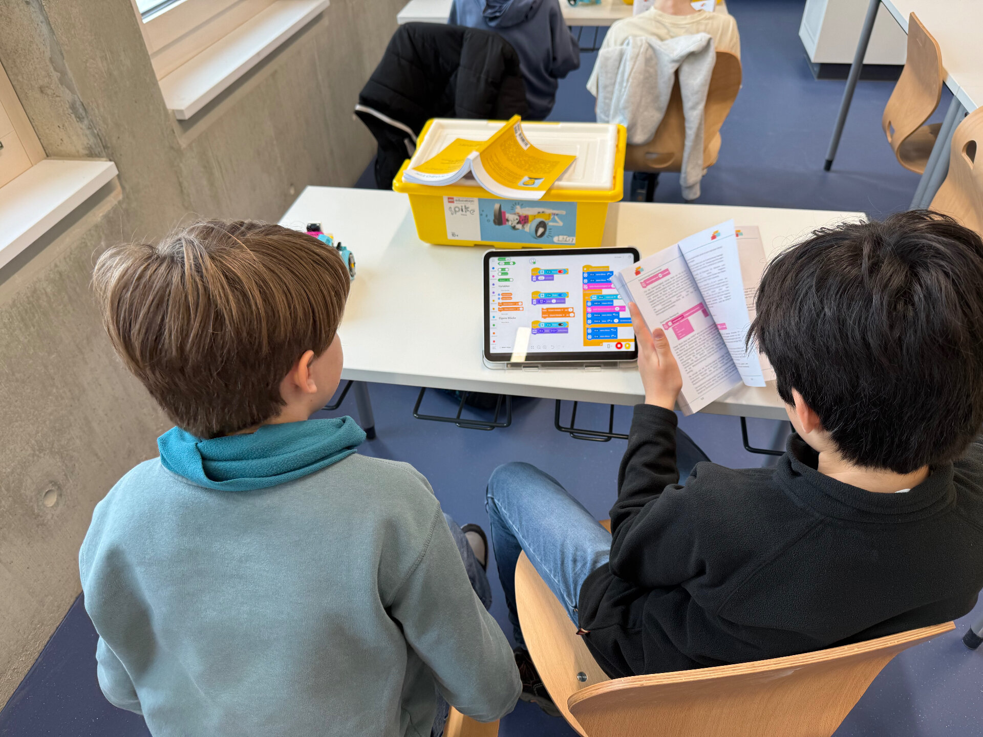 Two Robotics Club students programming a LEGO robot with a tablet and a Discovery Book